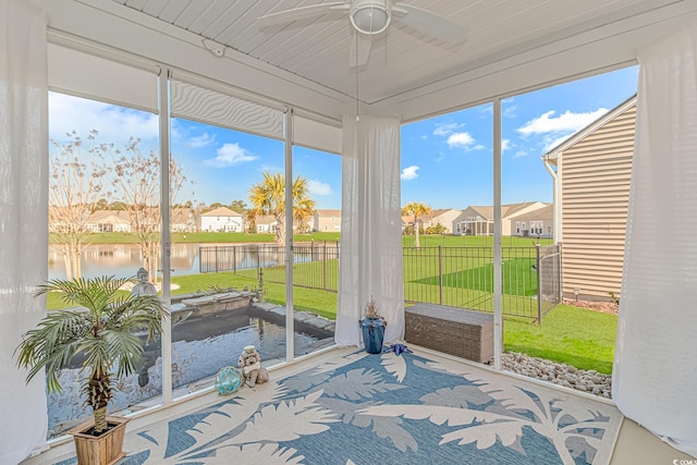 sunroom / solarium with ceiling fan, a residential view, and a water view