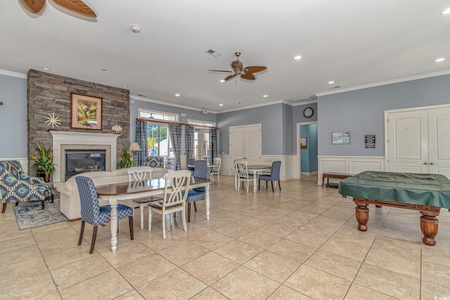 dining space with ceiling fan, crown molding, recessed lighting, wainscoting, and a large fireplace