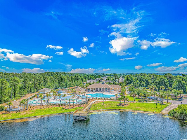 bird's eye view of a pool area, a heavily wooded area, and a nearby body of water