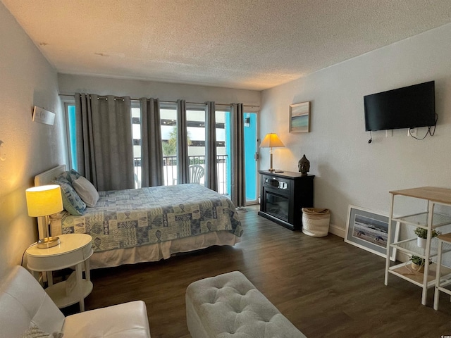 bedroom featuring a textured ceiling, baseboards, wood finished floors, and access to exterior