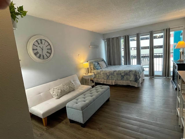 bedroom with access to exterior, a textured ceiling, and wood finished floors