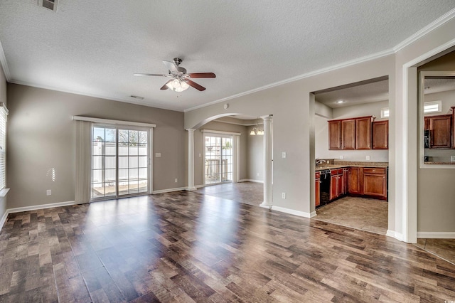 unfurnished living room with dark wood finished floors, decorative columns, a ceiling fan, and ornamental molding