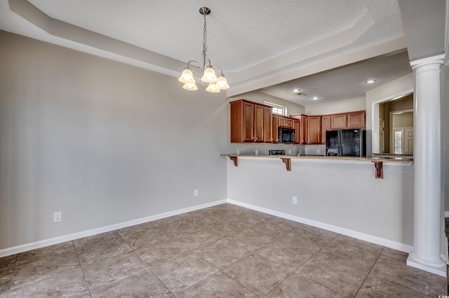 kitchen featuring baseboards, black appliances, a kitchen bar, and ornate columns