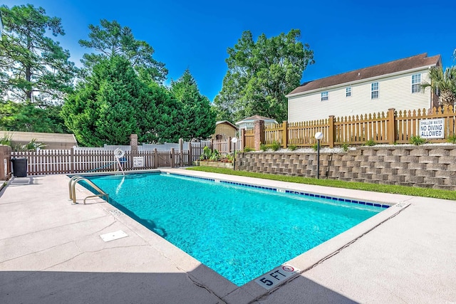 community pool with a patio area, a gate, and fence