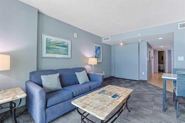 carpeted living area featuring a textured ceiling, visible vents, and recessed lighting