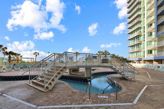 view of pool featuring a hot tub, stairs, and a patio