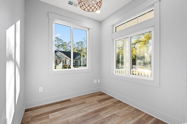 empty room featuring light wood-type flooring, baseboards, and visible vents