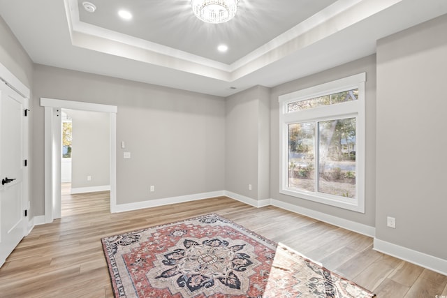 interior space featuring light wood-style floors, a tray ceiling, baseboards, and recessed lighting