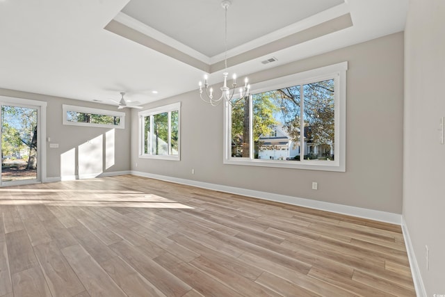 interior space with baseboards, a tray ceiling, ceiling fan with notable chandelier, and light wood-style floors