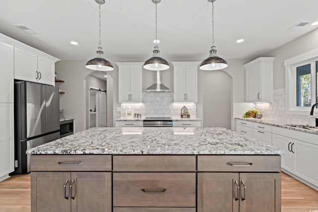 kitchen with arched walkways, a barn door, a sink, a kitchen island, and appliances with stainless steel finishes