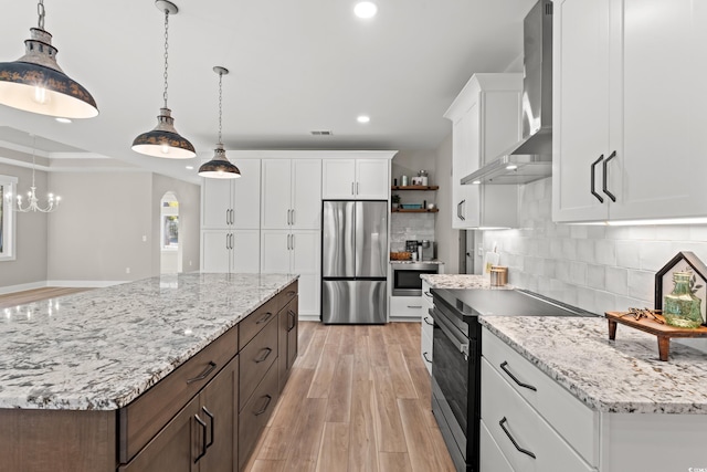 kitchen featuring stainless steel appliances, recessed lighting, tasteful backsplash, light wood-type flooring, and wall chimney exhaust hood