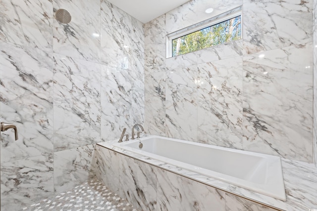 bathroom featuring a garden tub and a marble finish shower