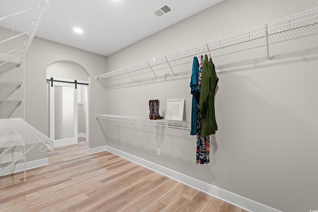 spacious closet with a barn door, wood finished floors, and visible vents