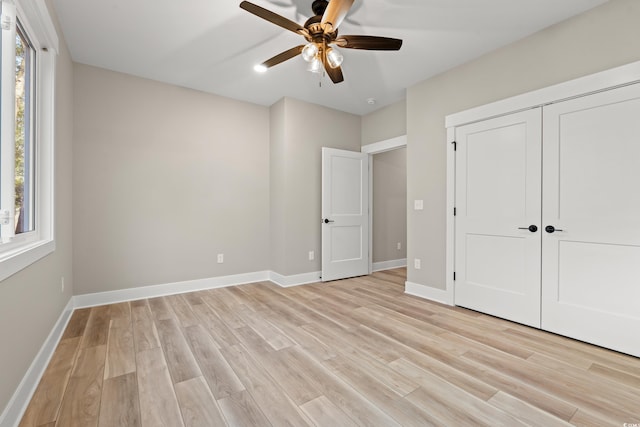 unfurnished bedroom with multiple windows, light wood-type flooring, and baseboards