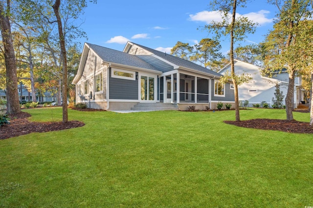 rear view of property featuring ceiling fan, a shingled roof, a lawn, and a sunroom