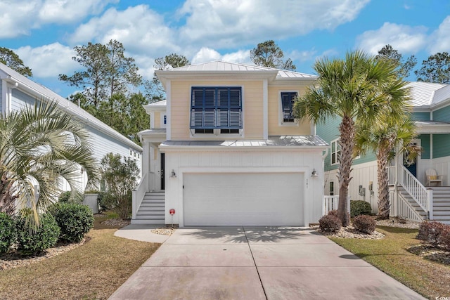 view of front of home featuring concrete driveway, stairway, metal roof, an attached garage, and a standing seam roof