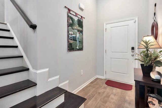 foyer with light wood-type flooring, stairs, and baseboards