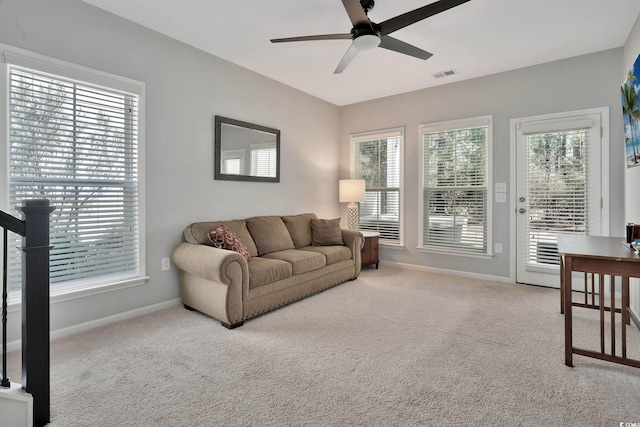 carpeted living area featuring baseboards, visible vents, and ceiling fan