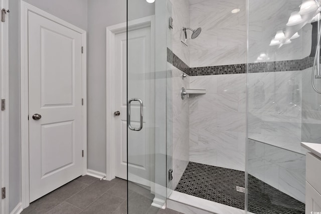 bathroom with a stall shower, vanity, and baseboards