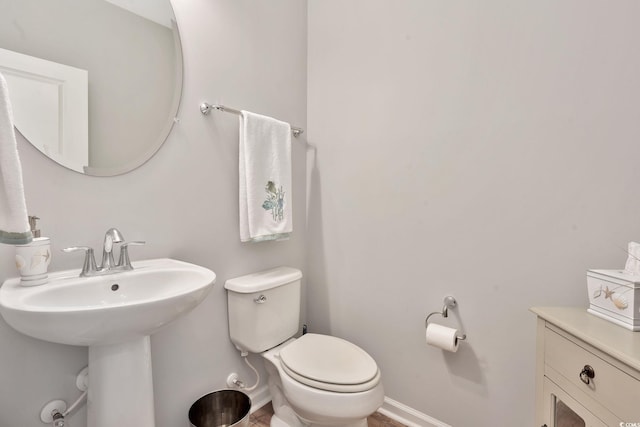 bathroom with toilet, baseboards, and a sink