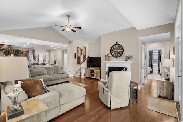 living area featuring a fireplace, ceiling fan, vaulted ceiling, and wood finished floors