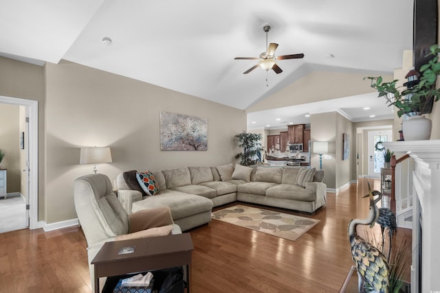 living area with a fireplace, ceiling fan, baseboards, and wood finished floors