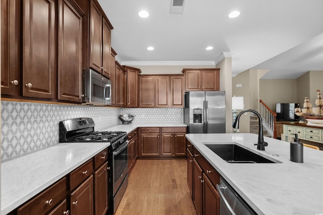 kitchen with a sink, visible vents, light wood-style floors, appliances with stainless steel finishes, and tasteful backsplash