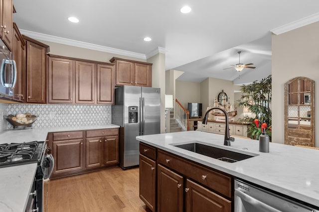 kitchen featuring appliances with stainless steel finishes, crown molding, a sink, and tasteful backsplash