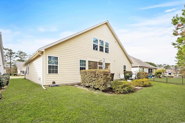 rear view of house with fence and a yard