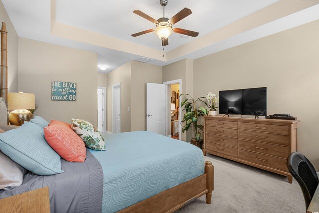 bedroom with light carpet, ceiling fan, visible vents, and a tray ceiling