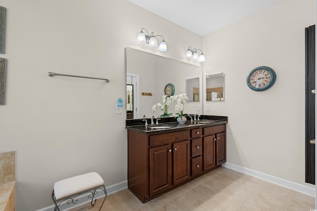 bathroom featuring baseboards, double vanity, and a sink