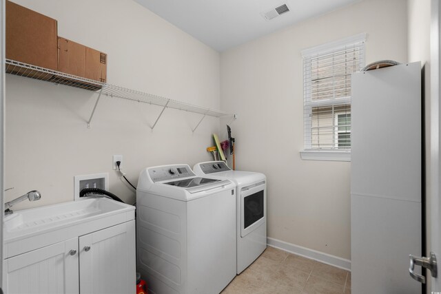 laundry room with cabinet space, baseboards, visible vents, separate washer and dryer, and a sink