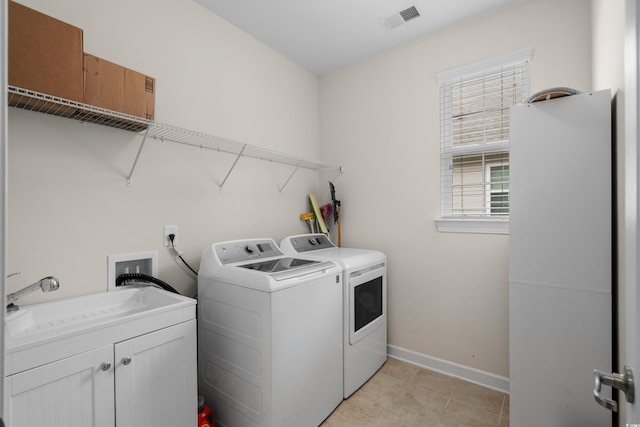 washroom with a sink, separate washer and dryer, baseboards, visible vents, and cabinet space