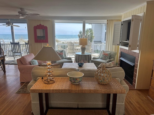 living room with a water view, a fireplace, ornamental molding, and wood finished floors