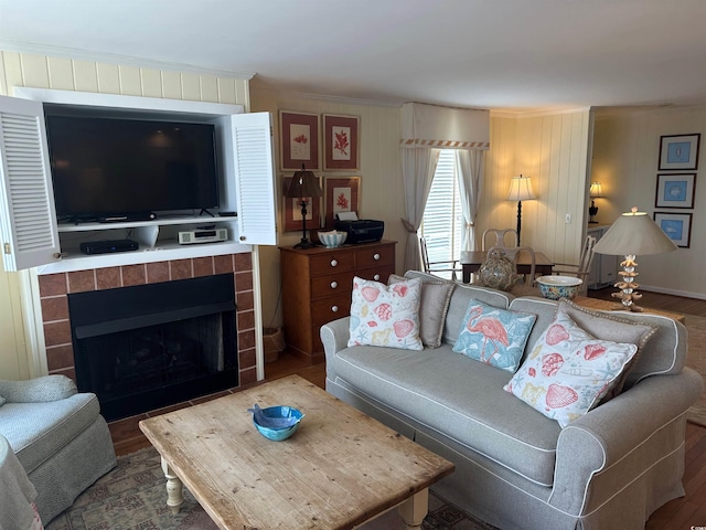 living area with ornamental molding, a fireplace, and wood finished floors