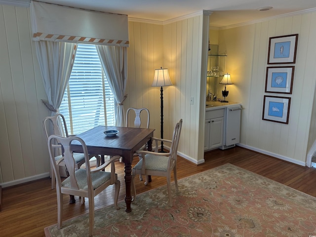 dining room featuring crown molding, baseboards, and wood finished floors