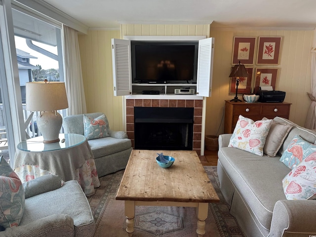 living area with ornamental molding, a fireplace, and wood finished floors