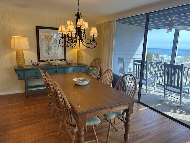 dining space featuring hardwood / wood-style flooring, baseboards, ornamental molding, and ceiling fan with notable chandelier