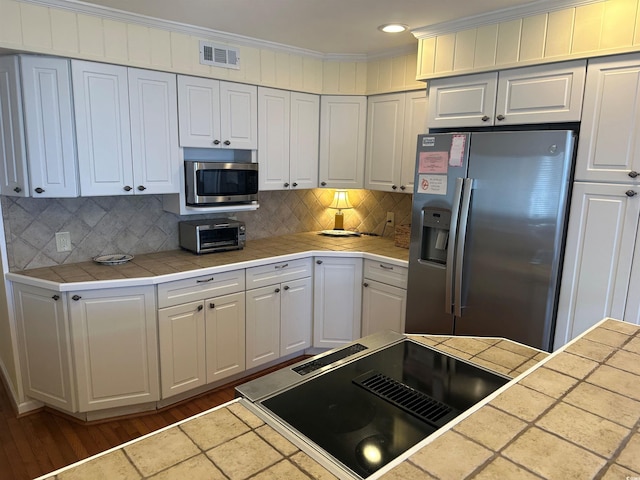 kitchen with a toaster, visible vents, appliances with stainless steel finishes, ornamental molding, and white cabinetry