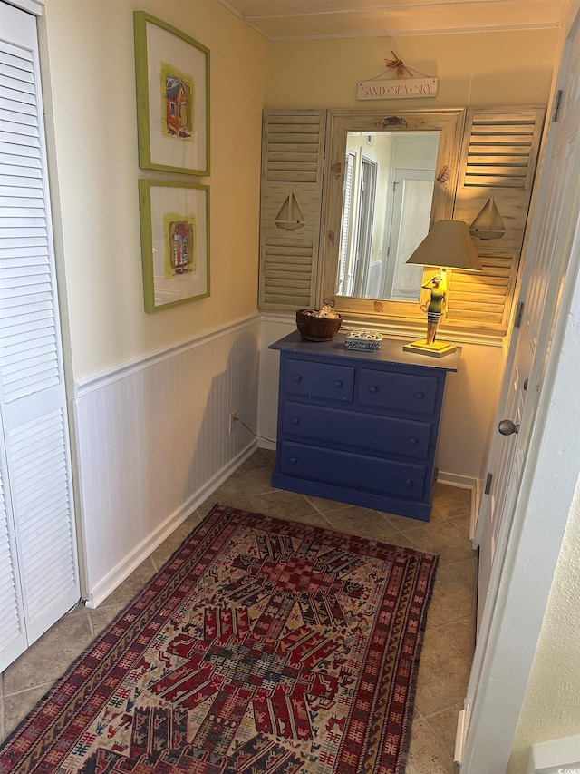 hallway featuring tile patterned floors and wainscoting