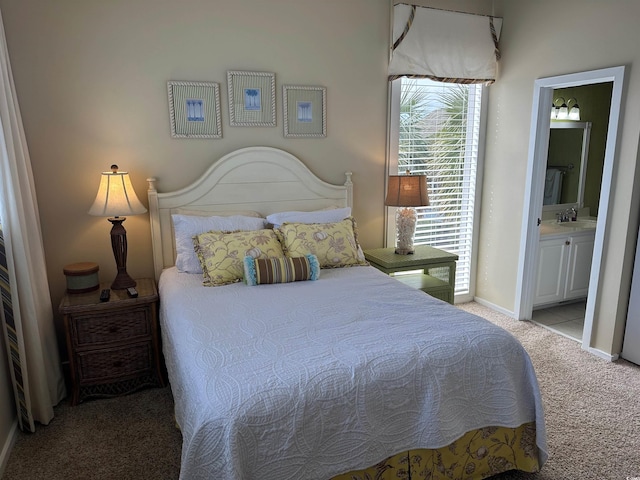 bedroom featuring light carpet, baseboards, a sink, and ensuite bathroom