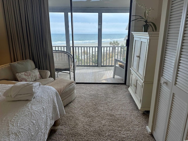 carpeted bedroom featuring a water view, a view of the beach, and access to exterior