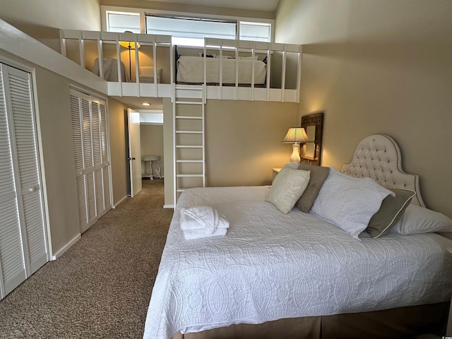 carpeted bedroom featuring a towering ceiling, baseboards, and two closets