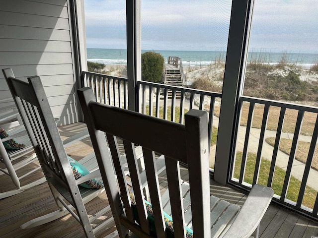 balcony with a water view and a view of the beach