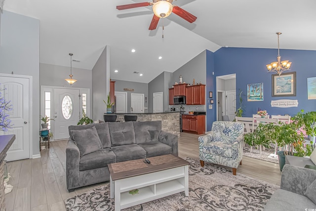 living area featuring light wood finished floors, high vaulted ceiling, and ceiling fan with notable chandelier