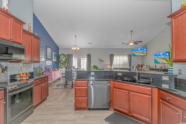 kitchen featuring light wood finished floors, vaulted ceiling, ceiling fan with notable chandelier, stainless steel appliances, and a sink