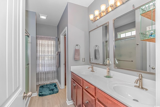 bathroom with double vanity, walk in shower, wood finished floors, and a sink