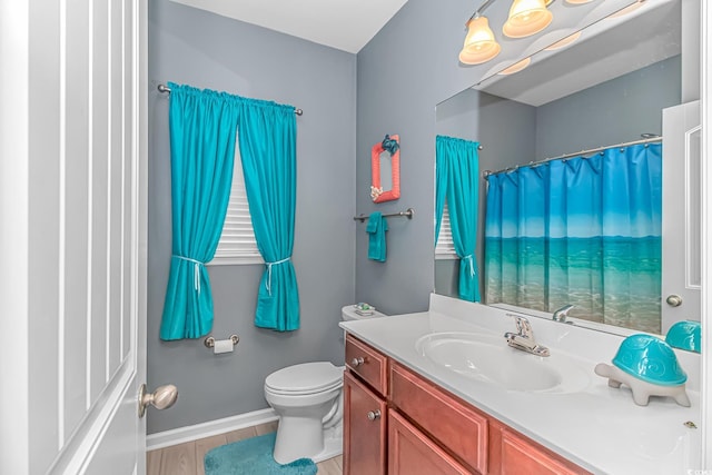 bathroom with toilet, vanity, and baseboards