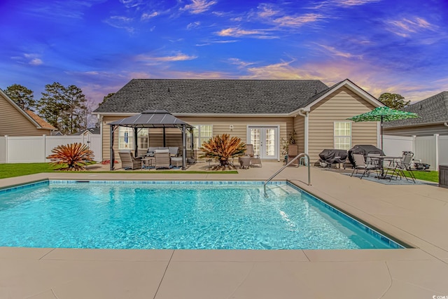 pool at dusk with a gazebo, a fenced in pool, a fenced backyard, and a patio area