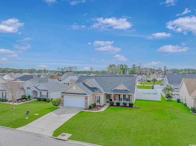 view of front of property with a residential view, concrete driveway, a front yard, and fence